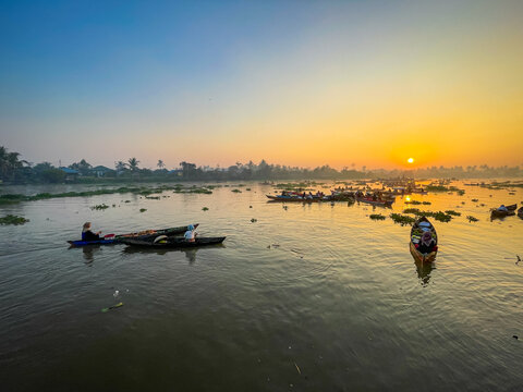 View of Lok Baintan Floating Market with traditional wooden boats on the river at sunrise, featuring local traders and calm water in Sungai Tabuk, South Kalimantan, Indonesia.