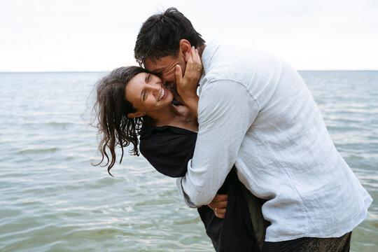 A man embraces a laughing woman at the beach