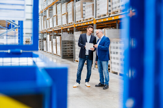 A manager and a businessman discuss logistics in a warehouse