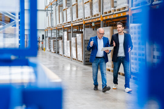 A manager and supervisor discuss logistics in a warehouse aisle