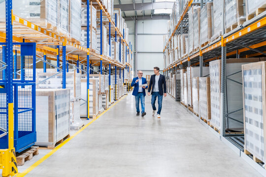 A businessman discusses logistics with a colleague in a warehouse