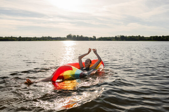 A girl floats on a colorful inflatable in a summer lake