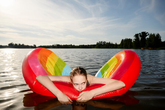 Girl uses a rainbow swimming aid in a summer lake