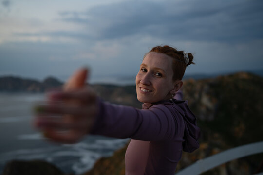 Smiling woman extends her hand outdoors to offer a warm welcome