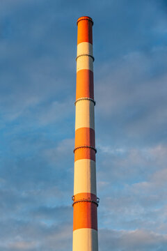 View of a tall industrial chimney with red and white stripes standing against a blue sky in Jaworzno, Silesian Voivodeship, Poland.