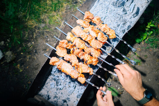 Man grilling meat shashlik on a skewer outside at a summer picnic