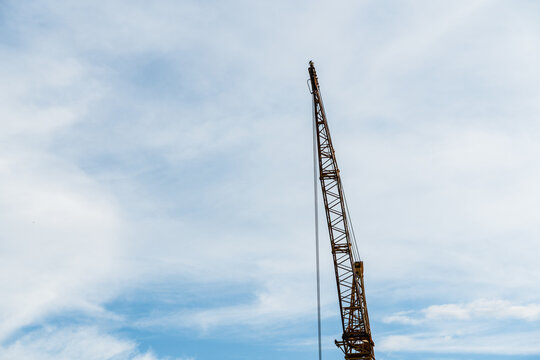View of a tall yellow construction crane reaching towards a blue sky with light clouds in Jaworzno, Silesian Voivodeship, Poland.