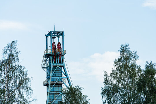 View of the industrial mine headframe with large red winding wheels against a clear sky in Jaworzno, Silesian Voivodeship, Poland.