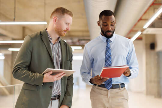Male colleagues discuss a document at the modern office