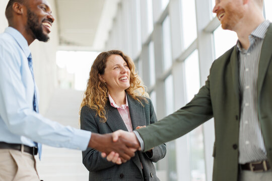 Smiling business partners shake hands in a bright office