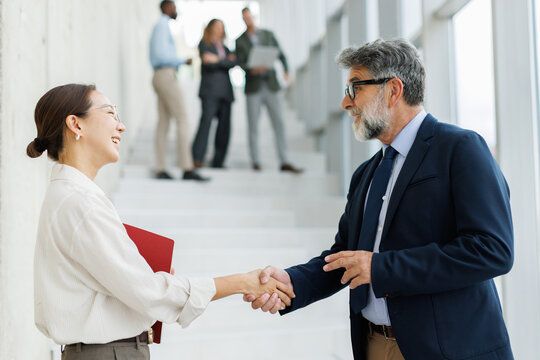 Smiling businessman and businesswoman shake hands in the office