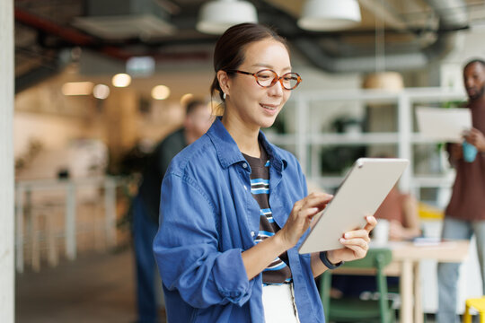 Smiling businesswoman uses a tablet in a modern coworking office