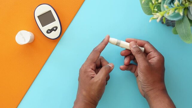 Person using a blood glucose meter for diabetes test by pricking finger with lancet device