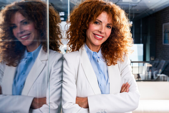 Smiling mature businesswoman looks at camera in the corporate office