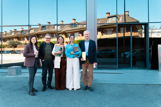 A business team stands together outside a modern office building