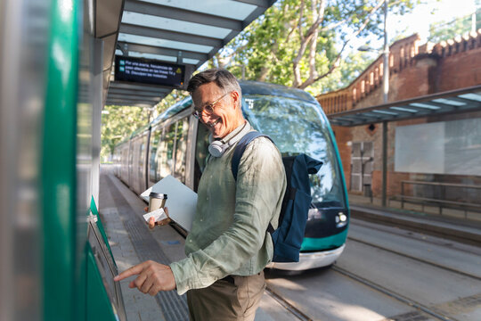 Smiling man buys a ticket at a tram station in Barcelona Spain