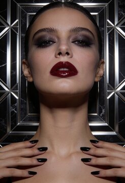 Elegant woman with dark makeup and stylish nails posing in studio  