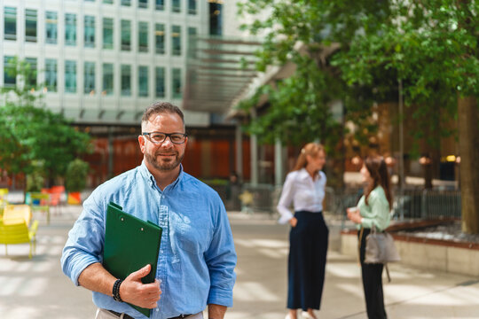 Smiling businessman holding clipboard outdoors in an urban office park
