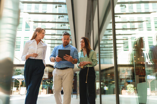 Business team reviews a corporate project on a tablet outdoors