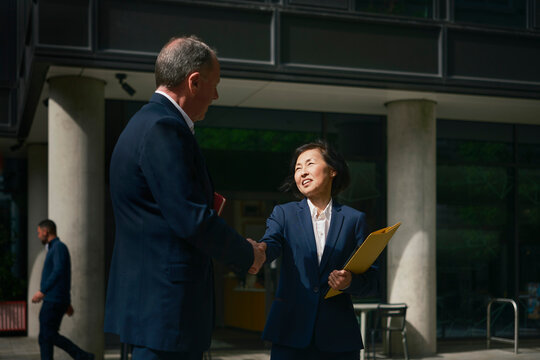 Businessman and businesswoman shake hands outside the office