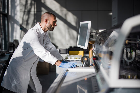 Male scientist analyses circuit board on computer in laboratory