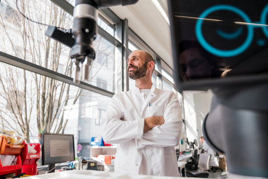 Confident scientist looks at a robot in the laboratory