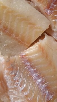 Raw fish fillet is spinning. Top view. Slices of fresh whitefish. Full frame. Sashimi rotation. Marine market. Vertical Video for sale. Cod, pollock loin steaks. Pangasius, tilapia pieces background