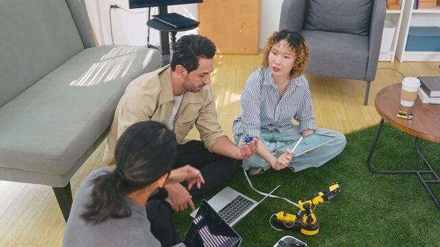 Team software engineers collaborating on robotics development and coding on laptops in startup office.