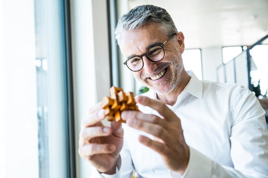 Smiling businessman holds a wooden puzzle in the office
