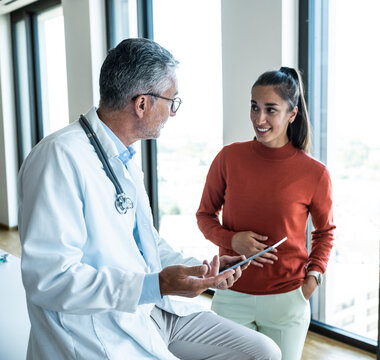 A doctor explains a medical diagnosis to a woman using a tablet