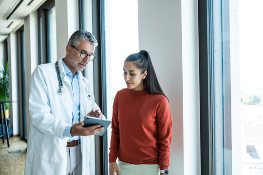Male doctor shows medical information to a patient on a tablet