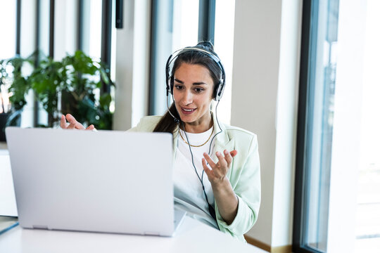 Smiling businesswoman with headset talking on video call at work