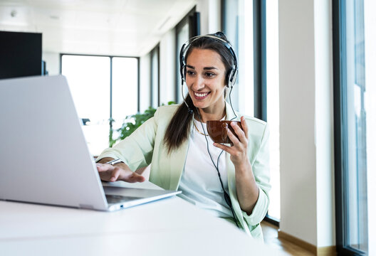 Smiling businesswoman works on a laptop at the office desk