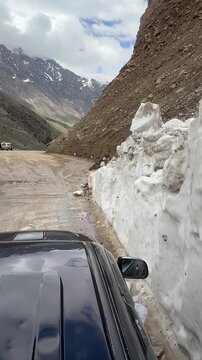 Snow-cleared dirt road framed by high ice walls along Babusar Pass in the Kaghan Valley.