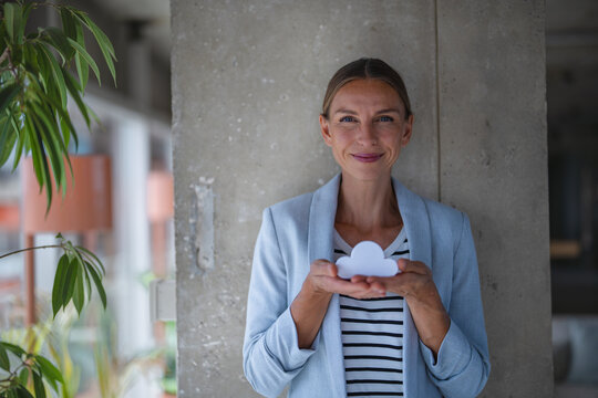 Smiling businesswoman holds a cloud symbol in a modern office