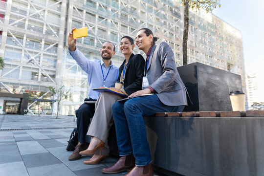 Happy colleagues take a selfie outside a modern building