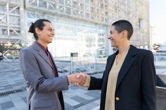 Businessman and businesswoman shake hands outdoors