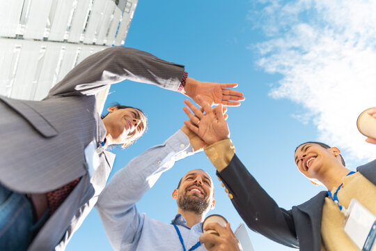 Business team puts hands together outdoors celebrating teamwork