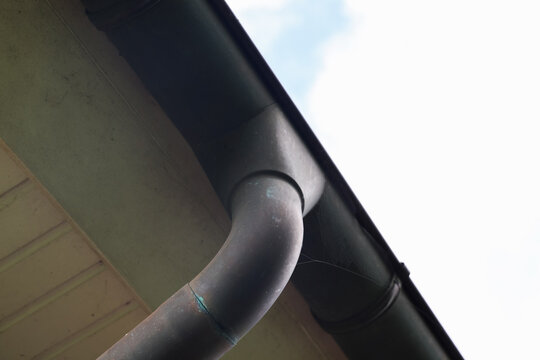 Old rain gutter downspout carrying water from roof