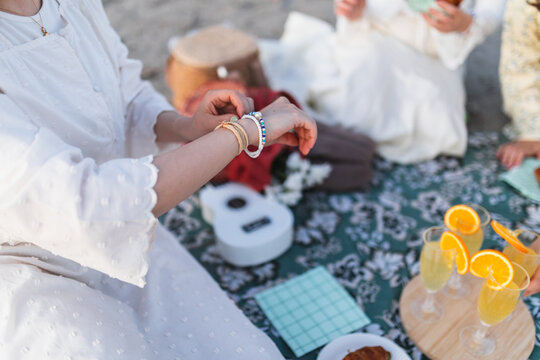 Woman adjusting bracelet at a summer beach picnic with friends
