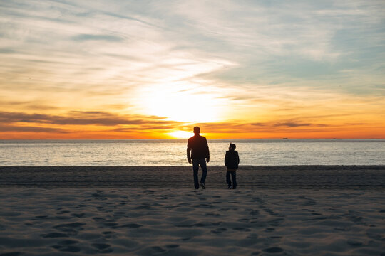 Father and son walking on the beach at sunset