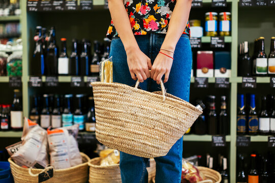 Mid section of customer holding basket in a store