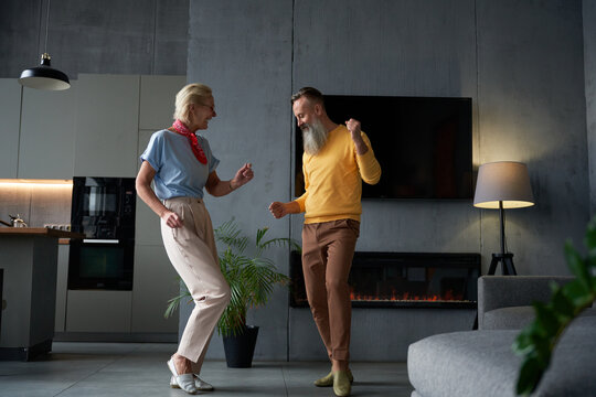 Happy couple is dancing together in their modern living room