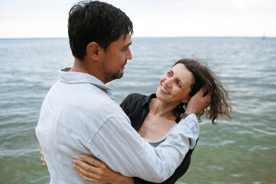 A happy couple embraces each other on the beach by the sea