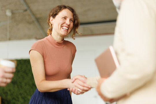 Smiling businesswoman shakes hands with male colleague at the office