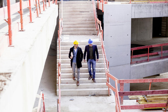 Two men on construction site walking down stairs