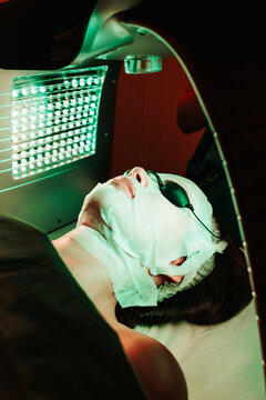 Woman receives facial treatment with led light in a beauty clinic