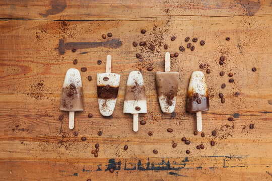 homemade Espresso Macchiato, Latte Macchiato and Cappuccino ice lollies with coffee beans on wooden background