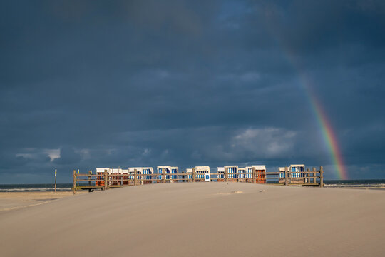 A rainbow appears over beach baskets in Sankt Peter Ording