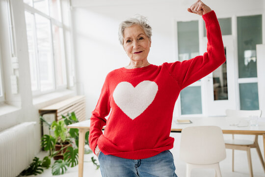 A brave woman flexes her bicep in a bright room